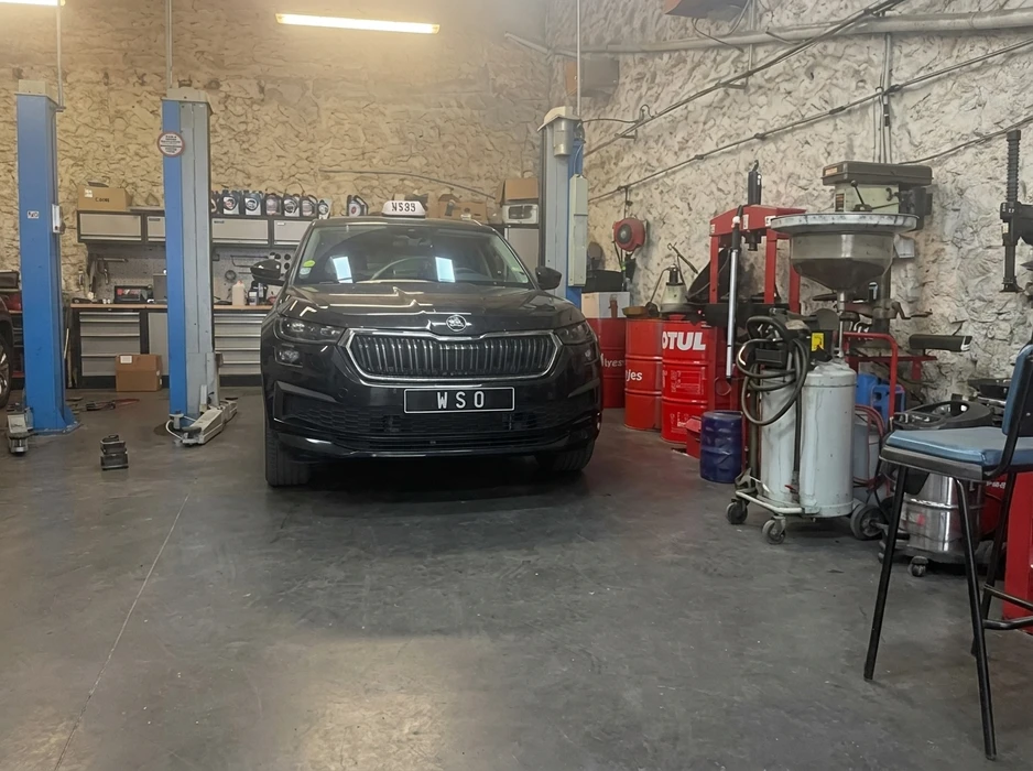 Garage automobile, intérieur, véhicule SUV Škoda Kodiaq noir immatriculé "WSO" positionné sur pont élévateur à colonnes