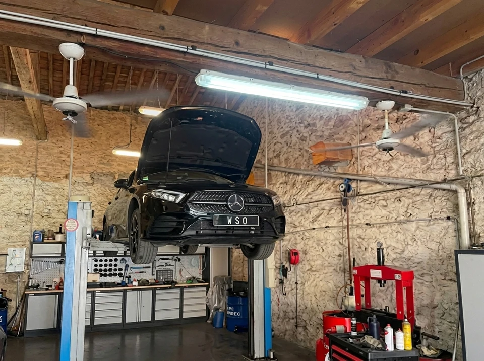 Garage automobile intérieur, Peugeot 308 noire sur pont élévateur à ciseaux, capot ouvert